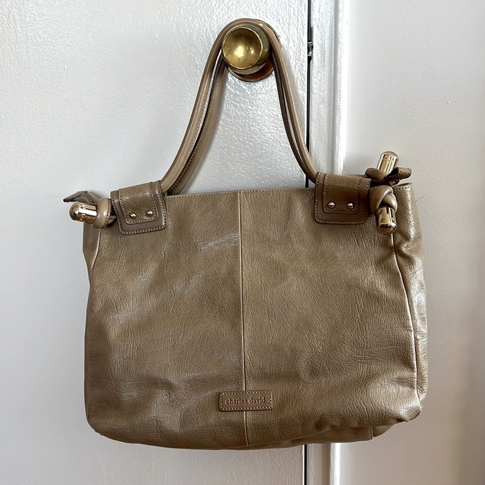 Leather bone beige bag with metal decorations on handles. Zippered